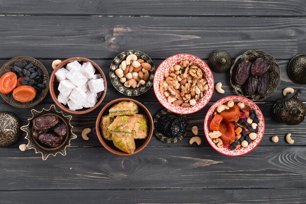 Uma visão aérea de doces árabes e frutas secas para o Ramadã na mesa de madeira preta