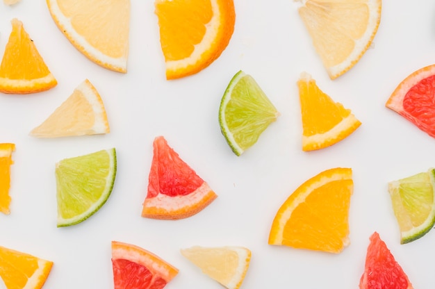 Uma visão aérea de fatias de frutas cítricas no pano de fundo branco