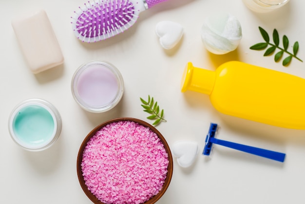 Uma visão aérea de sal rosa com produtos cosméticos no fundo branco