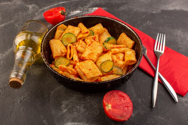 Uma visão frontal de massa italiana cozida com molho de tomate e pepino dentro de uma panela na mesa escura