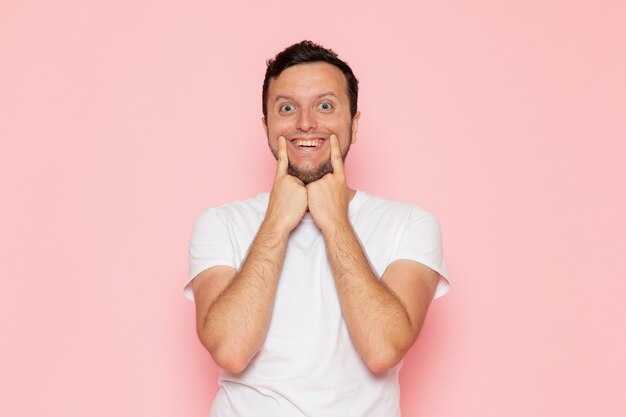 Uma visão frontal de um jovem do sexo masculino com uma camiseta branca mostrando os dentes