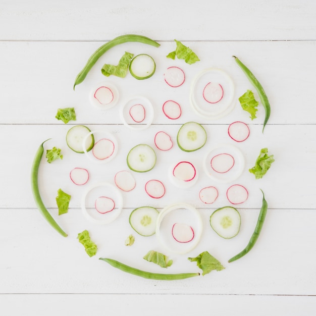 Uma visão geral do nabo; fatias de cebola e pepino com feijão verde e alface na mesa de madeira