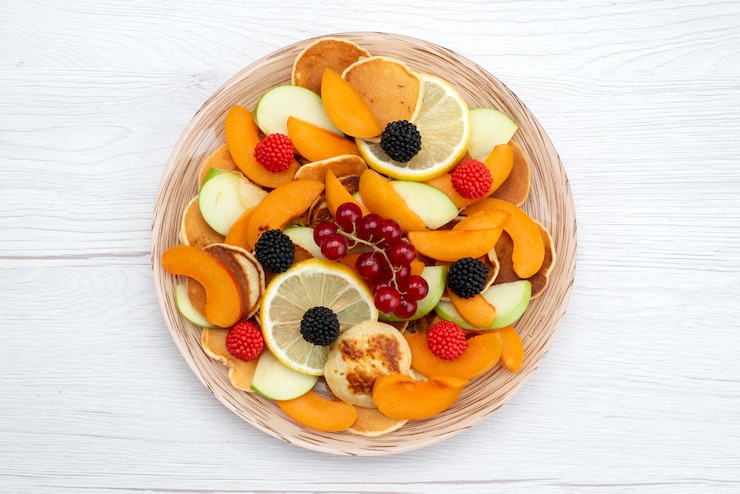 Foto grátis uma vista de cima com frutas frescas fatiadas coloridas e maduras na mesa de madeira e foto de comida colorida de frutas com fundo branco