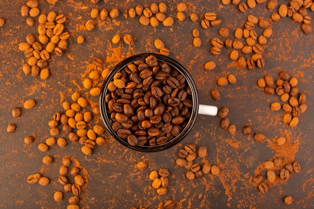 Uma vista de cima com sementes de café marrom dentro da tigela na mesa marrom