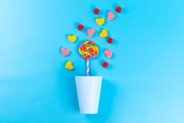 Uma vista de cima das geleias coloridas com pirulitos em uma confeitaria açucarada azul