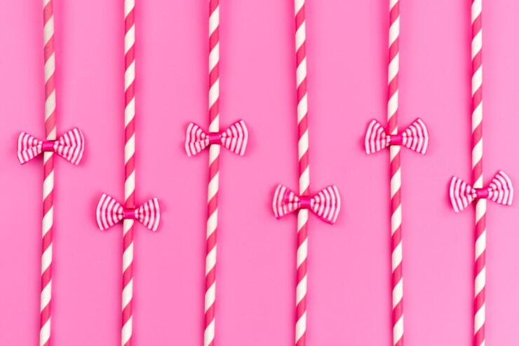 Foto grátis uma vista de cima de doces em forma de palito rosa-branco com laços na cor rosa doce