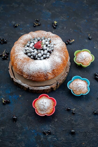 Uma vista de cima do bolo de frutas com azul fresco, bagas no escuro, biscoito doce com açúcar