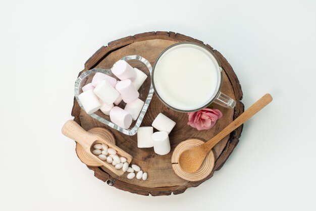 Uma vista de cima do marshmallow e do leite em uma madeira marrom e branca, doces de açúcar