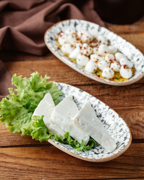 Uma vista de cima do queijo branco com salada verde na mesa de madeira marrom.