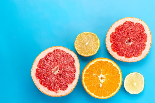 Uma vista de cima em fatias cítricas, toranjas, laranjas e limões na mesa azul, suco de frutas cítricas