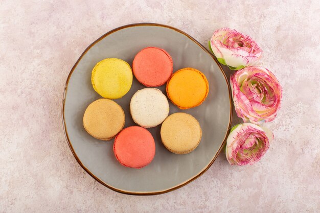 Uma vista de cima macarons franceses com rosas na mesa rosa bolo biscoito açúcar doce