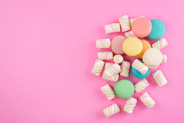 Uma vista de cima, macarons franceses e marshmallows na cor rosa e doce