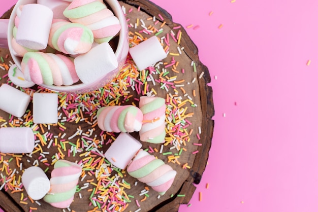 Uma vista de cima marshmallows rosa-brancos doces e pegajosos junto com partículas de doces coloridas em rosa