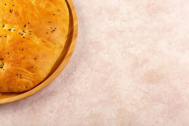 Uma vista de cima pão assado quente saboroso fresco dentro de mesa redonda em rosa