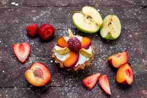 Foto grátis uma vista de cima, um bolo delicioso com creme e frutas frescas fatiadas na mesa marrom, bolo de frutas e biscoitos chá