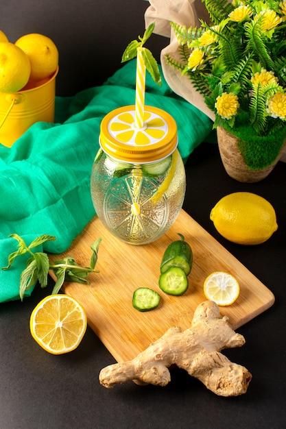 Uma vista frontal cocktail fresco limão bebida fresca dentro copo de vidro fatias e limões inteiros pepinos junto com flores sobre o fundo escuro coquetel bebida frutas