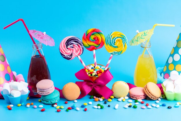 Uma vista frontal cocktails coloridos de refrigeração junto com pirulitos de macarons franceses e doces coloridos em azul