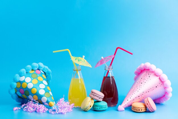Uma vista frontal colorido cocktails de refrigeração com macarons franceses e bonés engraçados em azul