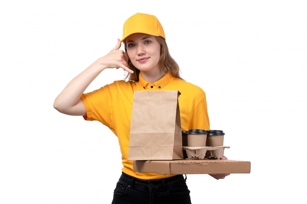 Foto grátis uma vista frontal correio feminino jovem trabalhadora do serviço de entrega de comida sorrindo segurando caixas de entrega de comida e mostrando um sinal de chamada em branco