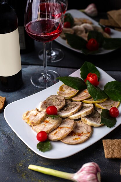 Uma vista frontal cortada patê dentro de chapa branca, juntamente com folhas verdes, batatas fritas de vinho tinto na mesa cinza