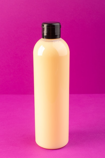 Foto grátis uma vista frontal creme shampoo de plástico de garrafa colorida pode com tampa preta, isolado no fundo roxo cosméticos beleza cabelo