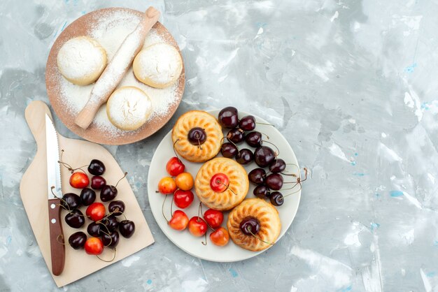 Uma vista frontal de biscoitos saborosos com cerejas dentro do prato e biscoito de massa