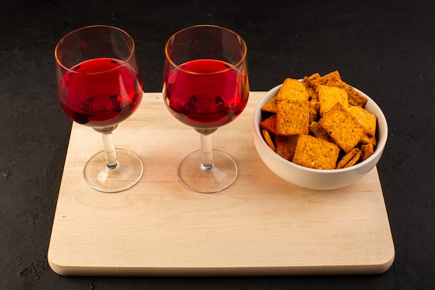 Foto grátis uma vista frontal de copos de vinho junto com batatas fritas dentro do prato na mesa de madeira e escuro