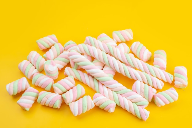 Uma vista frontal de marshmallows doces isolados em uma mesa amarela, cor de açúcar doce