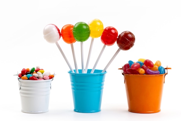 Uma vista frontal de pirulitos coloridos junto com balas multicoloridas dentro de baldes em cor de açúcar branco doce