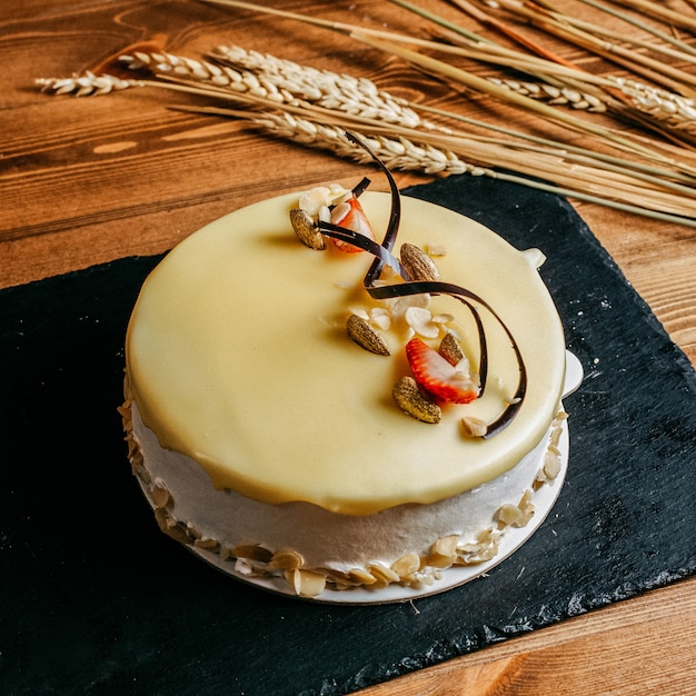 Uma vista frontal delicioso bolo de aniversário decorado gostoso redondo dentro de placa branca aniversário doce biscoito no fundo marrom