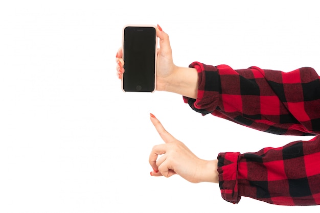 Uma vista frontal feminino mão na camisa quadriculada preto-vermelho segurando smartphone mostrando sinal de aviso no branco