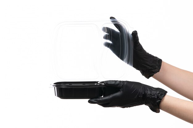 Uma vista frontal feminino mãos em luvas pretas, segurando a tigela com comida em branco