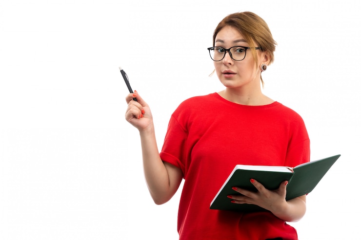 Foto grátis uma vista frontal jovem aluna em t-shirt vermelha segurando o caderno escrevendo notas em branco