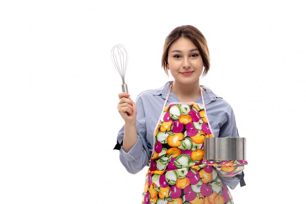 Uma vista frontal jovem bonita na camisa azul clara e capa colorida, segurando a bandeja de prata bolo feliz expressão a sorrir