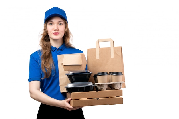 Uma vista frontal jovem correio feminino de boné azul camisa azul e calça preta segurando pacotes de entrega em branco