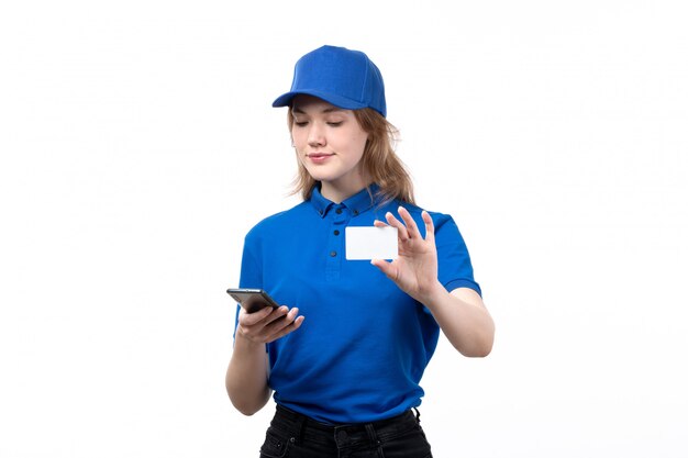 Uma vista frontal, jovem, correio feminino, trabalhadora, de, serviço entrega entrega, sorrindo, usando um telefone, e, cartão branco, branco