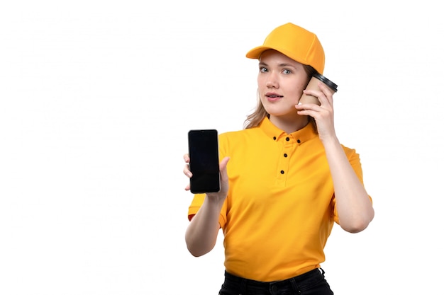 Uma vista frontal jovem correio feminino trabalhadora do serviço de entrega de comida segurando a xícara de café e smartphone em branco