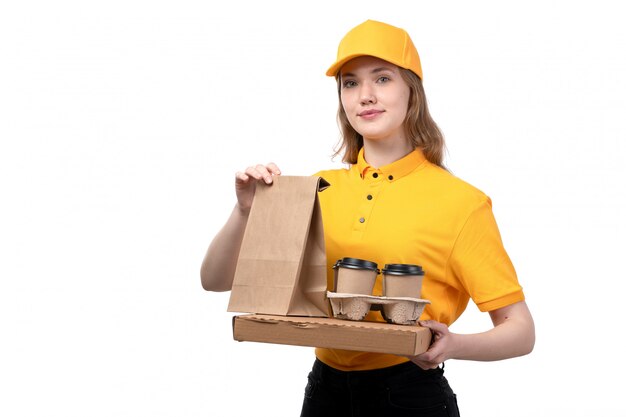 Uma vista frontal jovem correio feminino trabalhadora do serviço de entrega de comida segurando copos de café sorrindo em branco