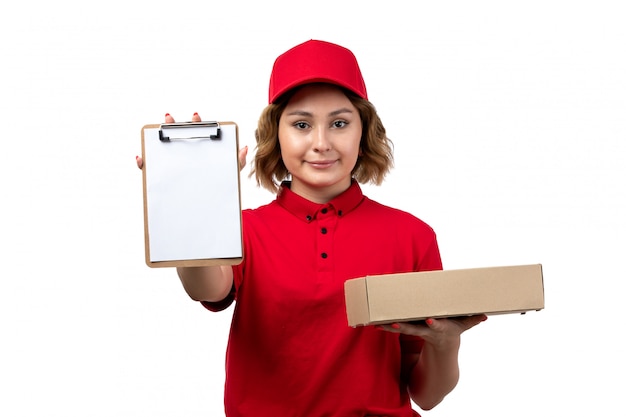 Uma vista frontal jovem correio feminino trabalhadora do serviço de entrega de comida segurando o pacote de alimentos e o bloco de notas em branco
