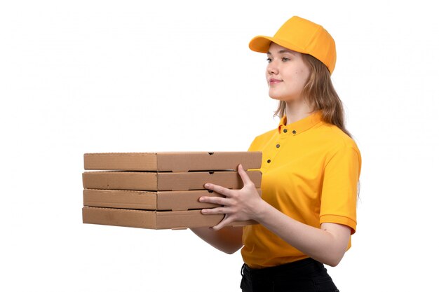 Uma vista frontal jovem correio feminino trabalhadora do serviço de entrega de comida sorrindo e entregando caixas com comida em branco