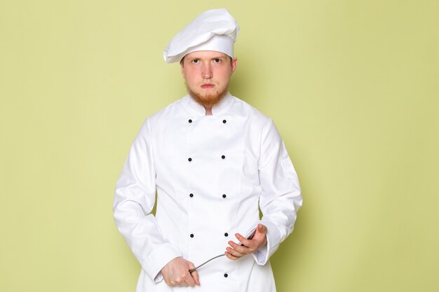Foto grátis uma vista frontal jovem cozinheiro masculino em branco cozinheiro terno branco cabeça boné com raiva