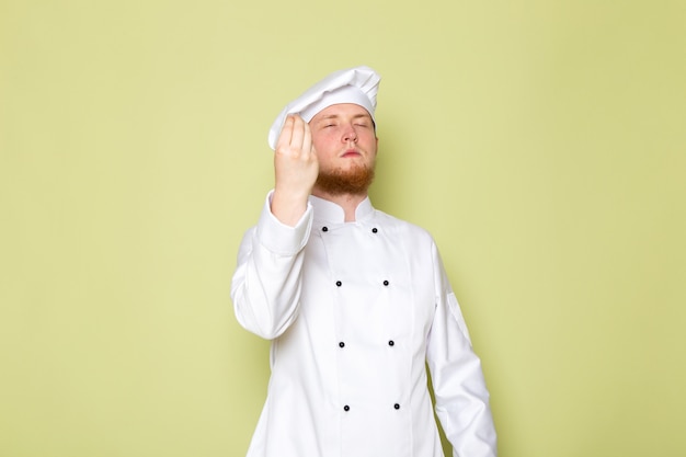 Uma vista frontal jovem cozinheiro masculino em branco cozinheiro terno branco cabeça cap saboroso sinal