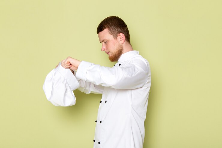 Foto grátis uma vista frontal jovem cozinheiro masculino em traje de cozinheiro branco usando boné de cabeça branca