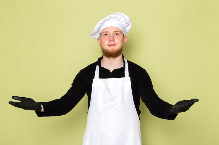 Foto grátis uma vista frontal jovem cozinheiro masculino na camisa preta com capa branca cabeça branca em luvas pretas posando