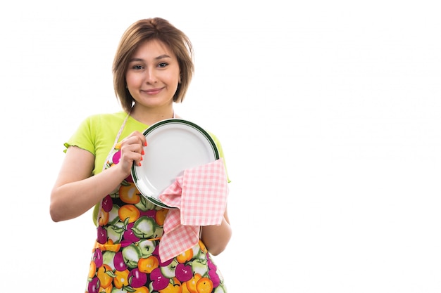 Foto grátis uma vista frontal jovem dona de casa bonita camisa verde camisa colorida limpeza placa de secagem sorrindo sobre o fundo branco casa limpeza cozinha