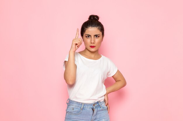 Uma vista frontal jovem fêmea em t-shirt branca e azul jeans posando