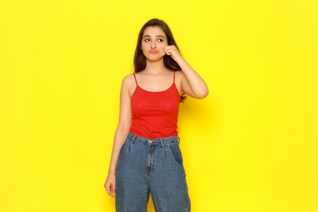 Uma vista frontal jovem garota bonita camisa vermelha e calça jeans azul, tirando a bochecha