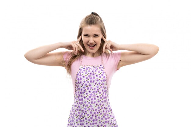 Uma vista frontal jovem linda dona de casa na camisa rosa capa colorida gritando grito posando com as mãos