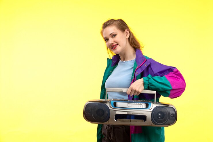 Foto grátis uma vista frontal jovem mulher moderna na camisa azul calça preta jaqueta colorida sorrindo posando segurando o gravador