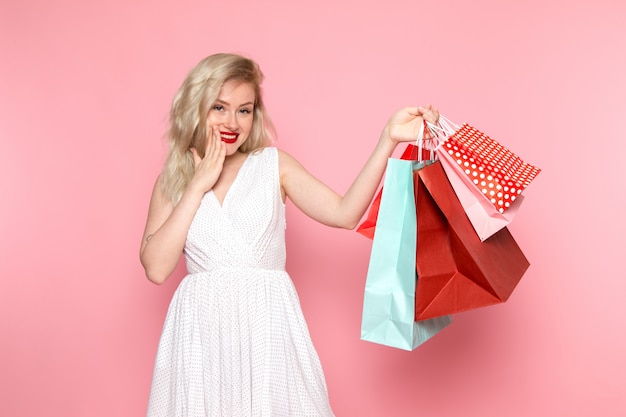 Uma vista frontal linda moça de vestido branco segurando pacotes de compras com sorriso no rosto